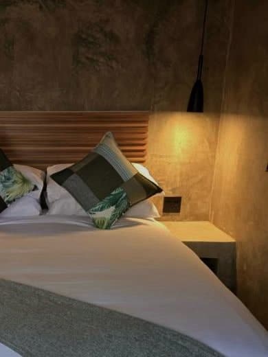 A corner of the bed, lit by a bedside lamp